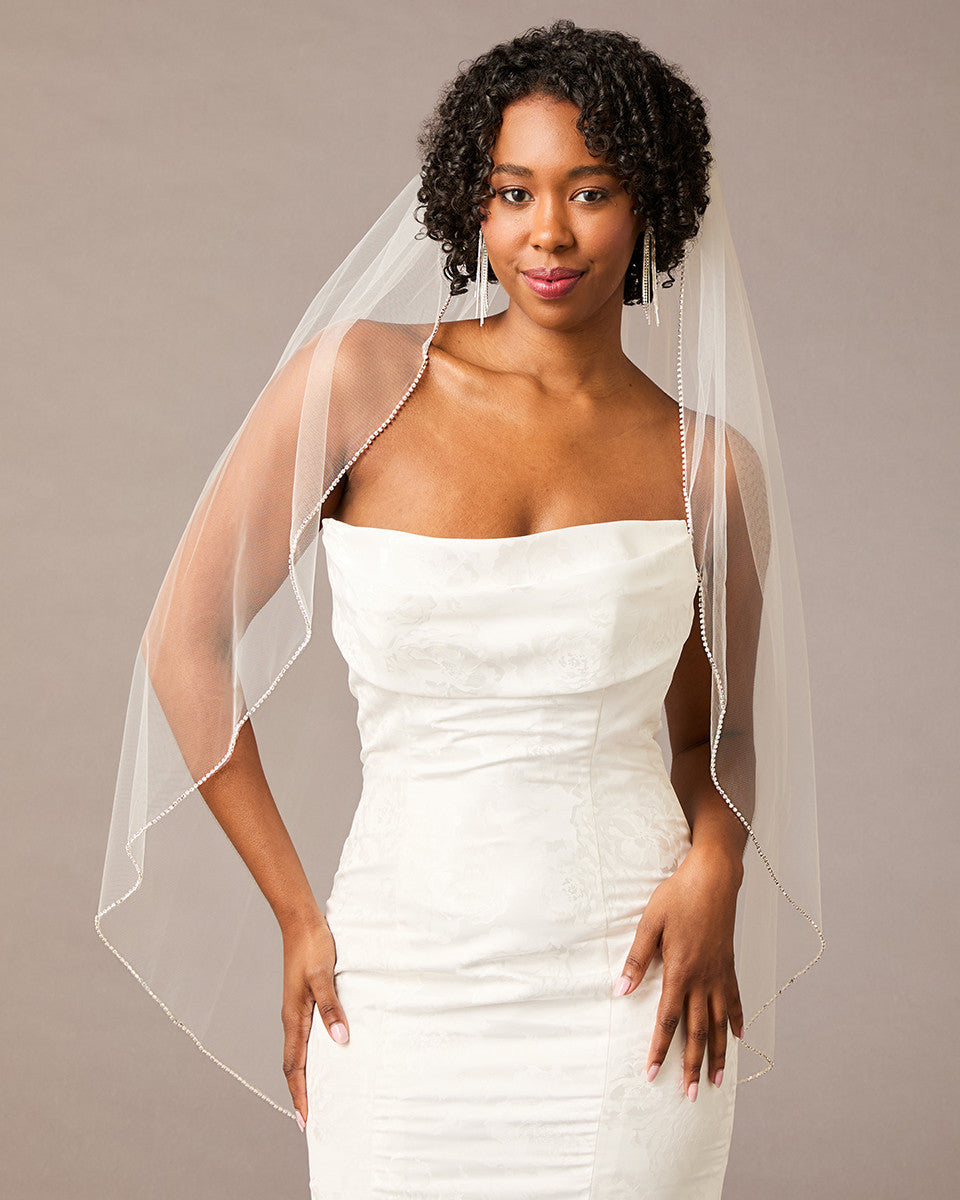 Fingertip Bridal Veil with Rhinestone Chain Trim Woman wearing a wedding dress with a sheer veil against a plain background