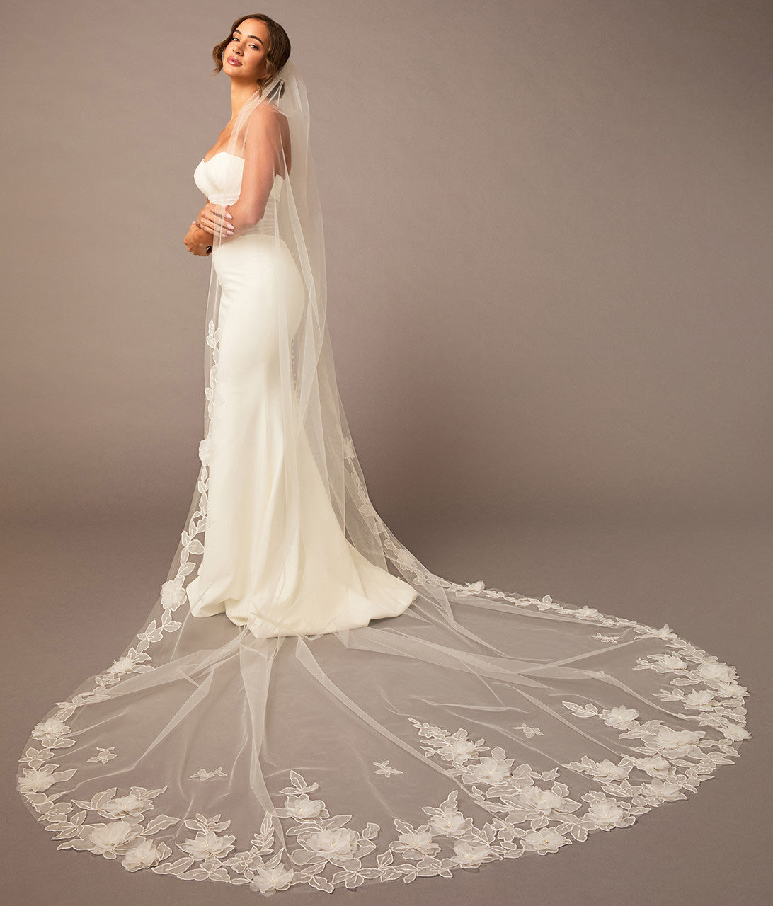 Woman wearing a white wedding dress with a long, elegant veil against a plain background Partial Lace and Organza Flowers Cathedral Wedding Veil