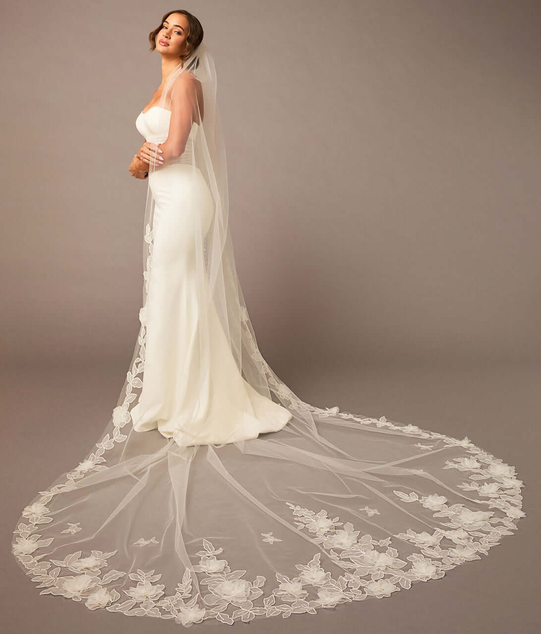 Woman wearing a white wedding dress with a long, elegant veil against a plain background Partial Lace and Organza Flowers Cathedral Wedding Veil