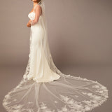 Woman wearing a white wedding dress with a long, elegant veil against a plain background Partial Lace and Organza Flowers Cathedral Wedding Veil