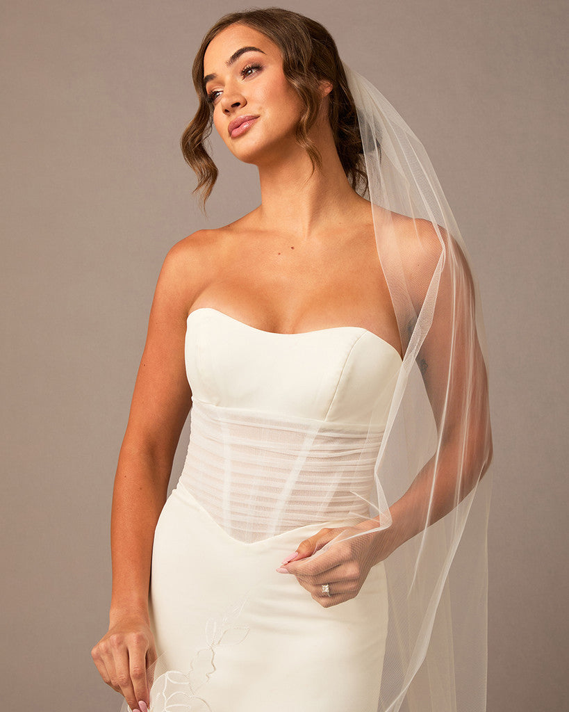 Woman wearing a white strapless wedding dress with a sheer veil against a neutral background Partial Lace and Organza Flowers Cathedral Wedding Veil