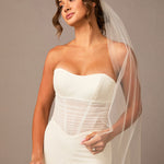 Woman wearing a white strapless wedding dress with a sheer veil against a neutral background Partial Lace and Organza Flowers Cathedral Wedding Veil