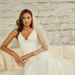 Cathedral Veil with Scattered Clusters of Crystal Beads Woman in a  wedding dress sitting on a couch against a brick wall.