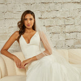 Cathedral Veil with Scattered Clusters of Crystal Beads Woman in a  wedding dress sitting on a couch against a brick wall.