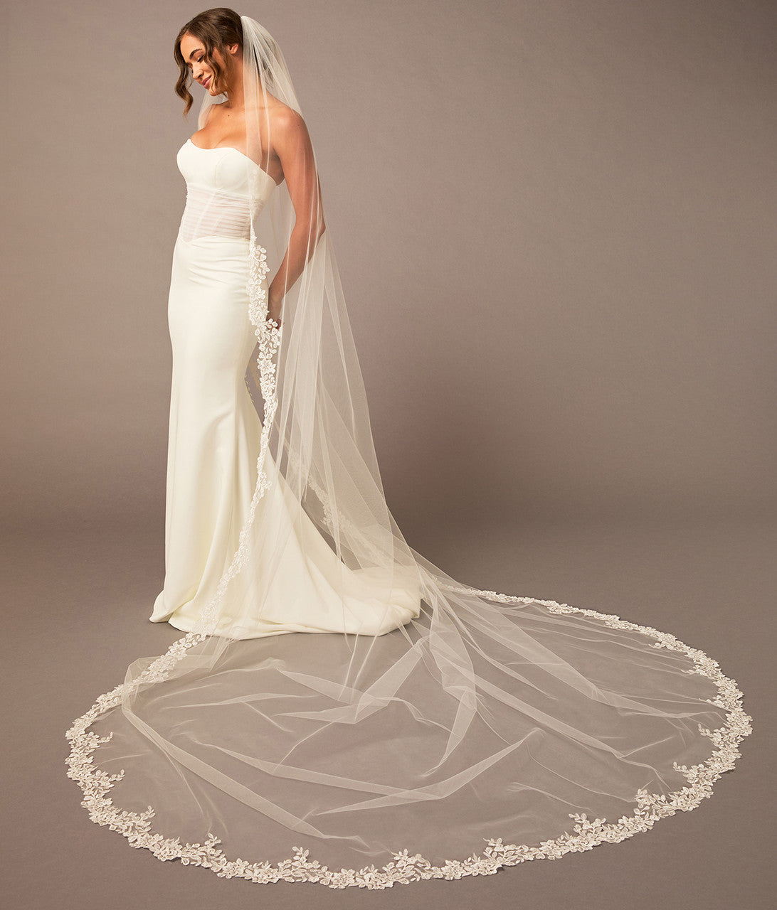 Partial Lace Trim Cathedral Bridal Veil Woman wearing a wedding dress with a long veil on a brown background