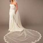 Partial Lace Trim Cathedral Bridal Veil Woman wearing a wedding dress with a long veil on a brown background