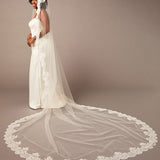 Woman wearing a long white wedding veil with lace details on a brown  Mantilla Cathedral Veil with Wide Flower Chantilly Lacebackground