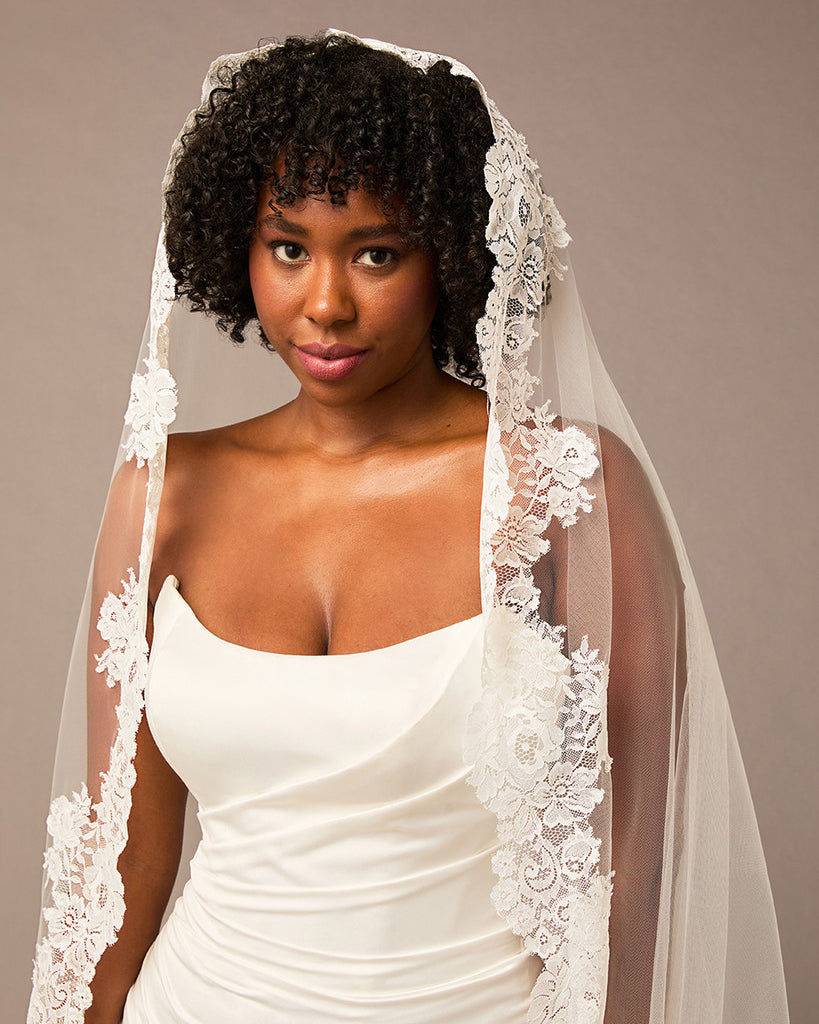Woman wearing a white wedding dress with a lace veil against a neutral background Mantilla Cathedral Veil with Wide Flower Chantilly Lace