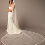  Bridal Veil with Scalloped Small Eyelash Lace Woman wearing a white wedding dress with a long veil against a plain background