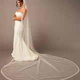  Bridal Veil with Scalloped Small Eyelash Lace Woman wearing a white wedding dress with a long veil against a plain background