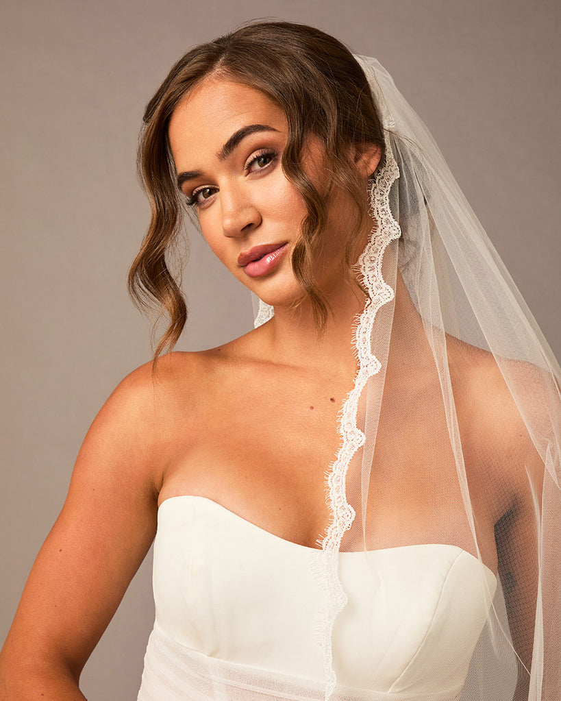 Bridal Veil with Scalloped Small Eyelash Lace Woman wearing a white strapless dress and veil against a neutral background