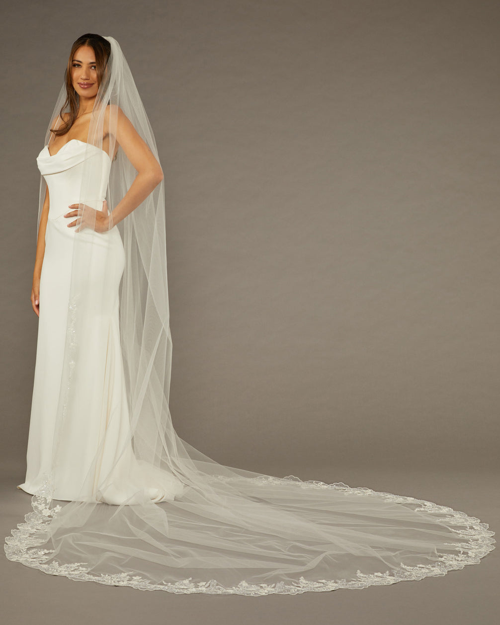 Cathedral Wedding Veil Finished Scallop Edge and Beads Woman wearing a wedding dress with a long veil against a brown background