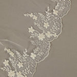 Cathedral Wedding Veil Finished Scallop Edge and Beads Close-up of lace fabric with floral patterns on a beige background