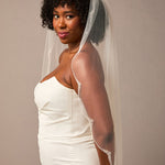 Scalloped Bridal Veil Covered in Pearls and Beads Woman wearing a wedding dress with a veil against a plain background