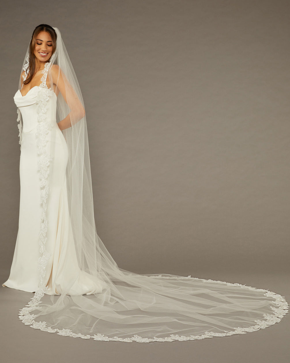 Sequined Lace Bridal Veil Royal Cathedral Length Woman wearing a wedding dress with a long veil against a brown background