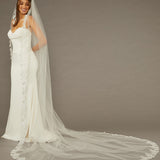 Sequined Lace Bridal Veil Royal Cathedral Length Woman wearing a wedding dress with a long veil against a brown background