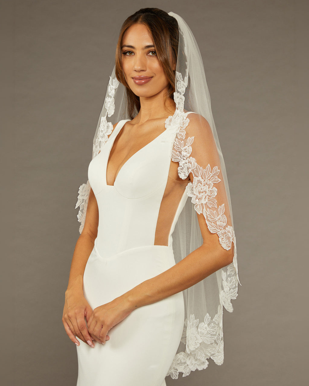 Sequined Lace Bridal Veil Fingertip Length Woman wearing a wedding dress with a lace veil against a brown background