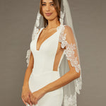 Sequined Lace Bridal Veil Fingertip Length Woman wearing a wedding dress with a lace veil against a brown background