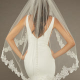 Sequined Lace Bridal Veil Fingertip Length Bride wearing a  wedding dress with a lace-trimmed veil against a dark background