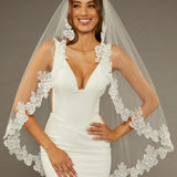 Sequined Lace Bridal Veil Fingertip Length Woman wearing a wedding dress with a lace veil against a neutral background