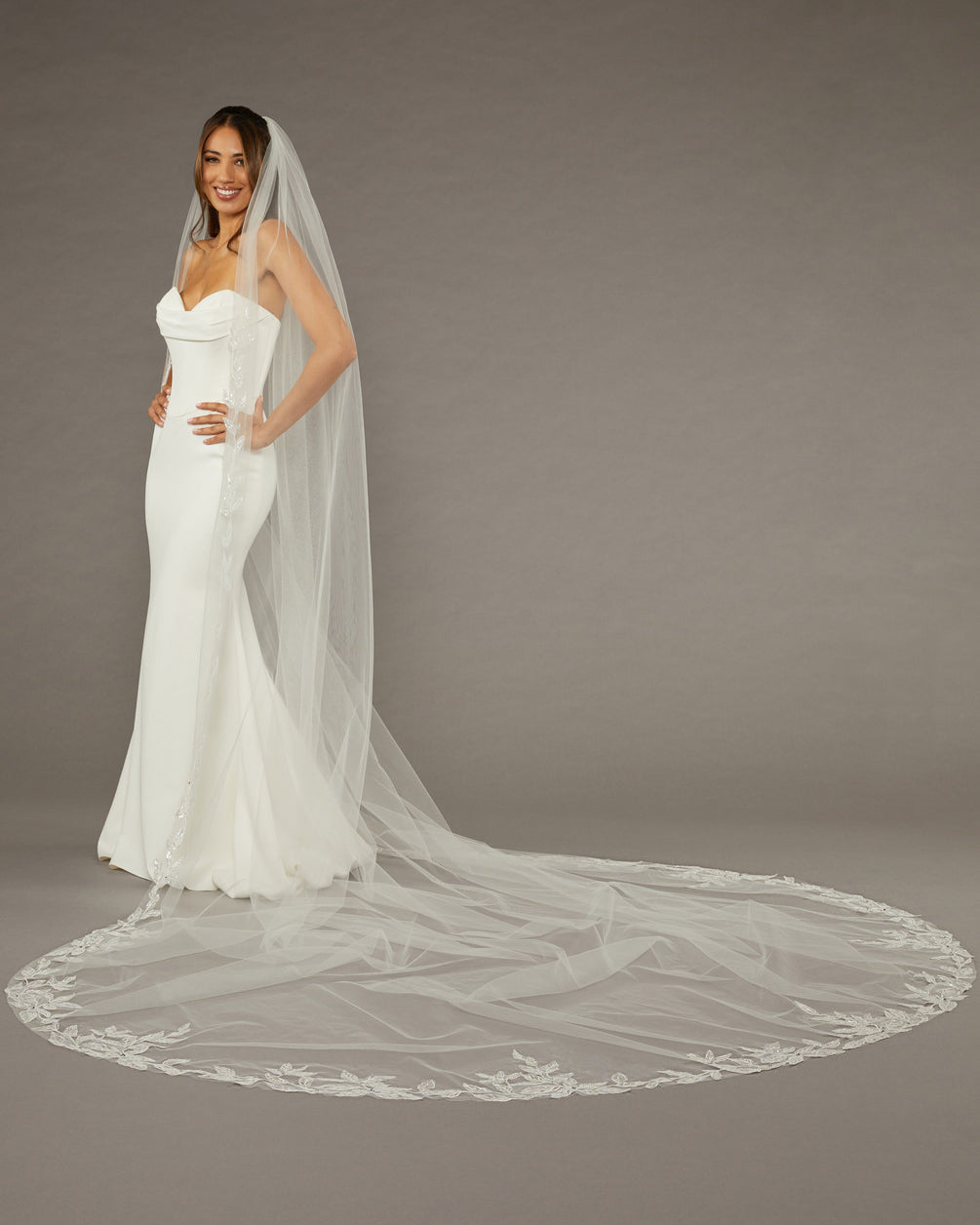 Beaded Leaves Cathedral Wedding Veil Woman wearing a wedding dress with a long veil on a gray background