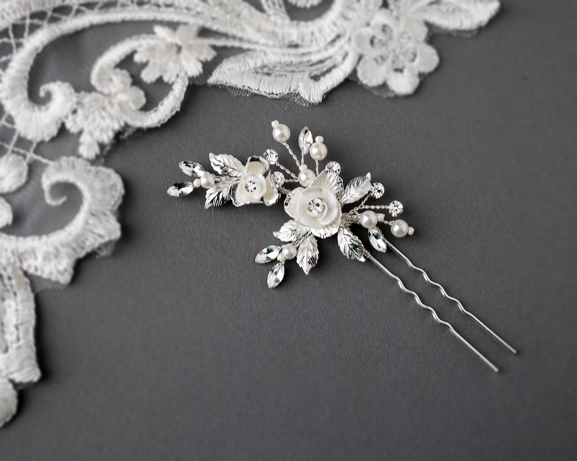 This stunning hair pin features bright porcelain flowers in ivory, adorned with marquise crystal stones for a sophisticated look that adds a subtle sparkle to your bridal hairstyle. Crafted from silver or light gold leaves and petals, this decorative piece measures 2.75 by 1.75 inches, making it the perfect choice for any blushing bride.