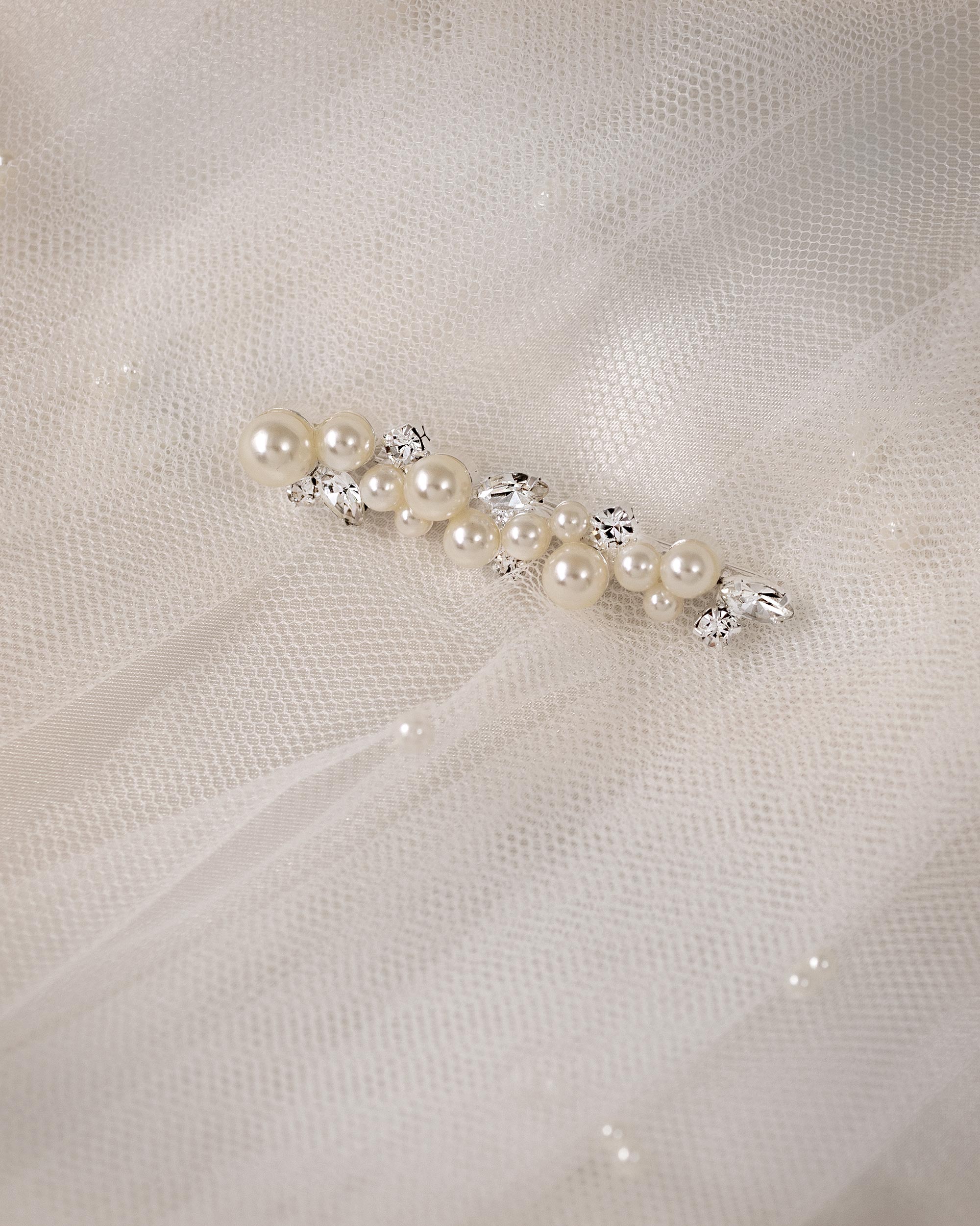 Bridal Bobby Pin with Ivory Pearls A pearl and crystal hair accessory displayed on a soft white tulle fabric background.