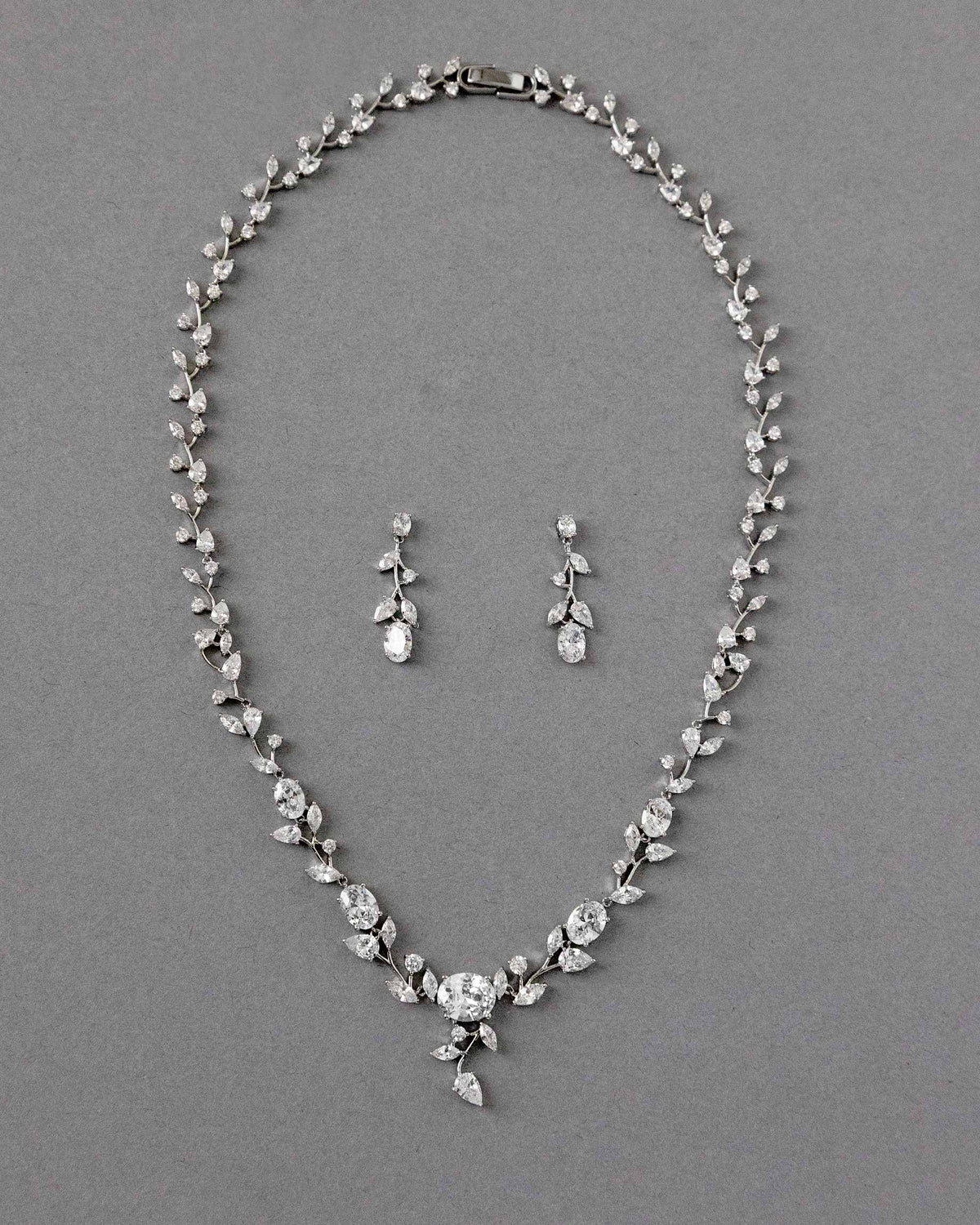 A bridal necklace set with dainty oval vines and sparkling oval CZ gems, displayed on a gray surface.