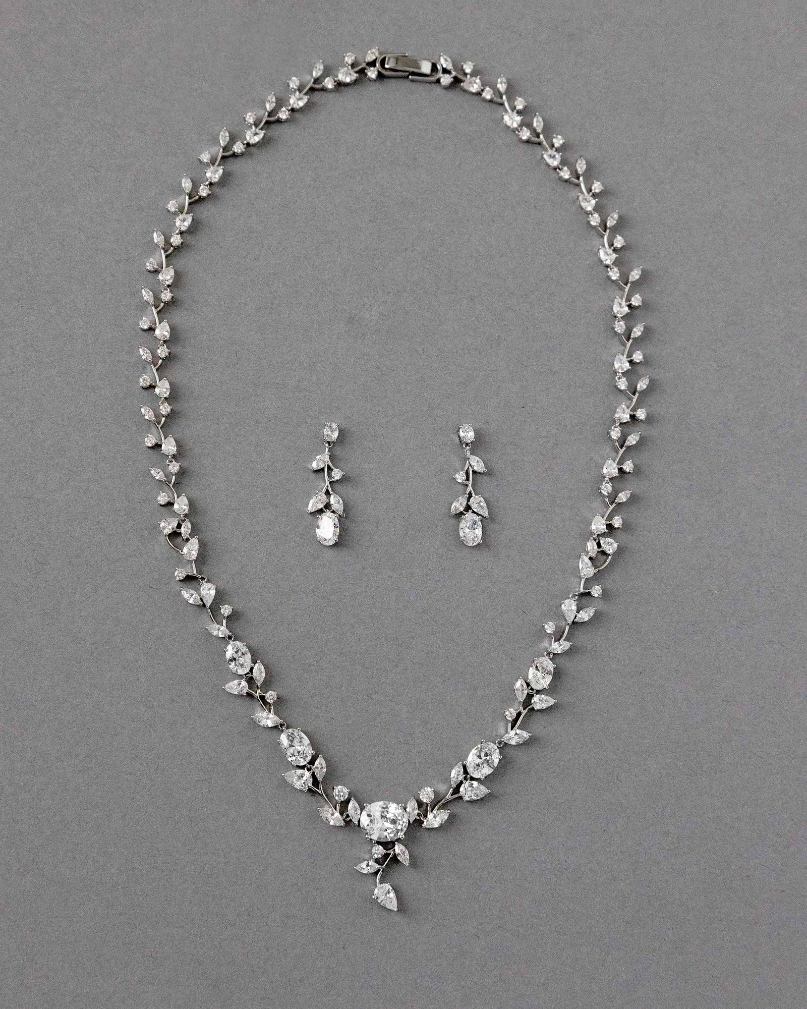A bridal necklace set with dainty oval vines and sparkling oval CZ gems, displayed on a gray surface.