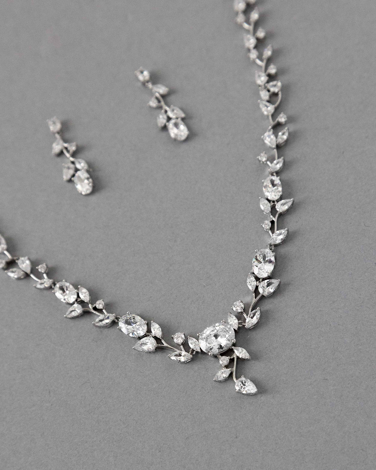 A bridal necklace set with dainty oval vines and sparkling oval CZ gems, displayed on a gray surface.