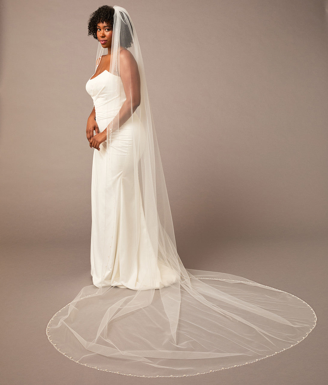 Zig Zag Teardrop Pearl Trimmed Cathedral Bridal Veil Woman wearing a wedding dress with a long veil on a plain background
