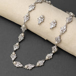 Silver necklace and earrings set on a gray surface