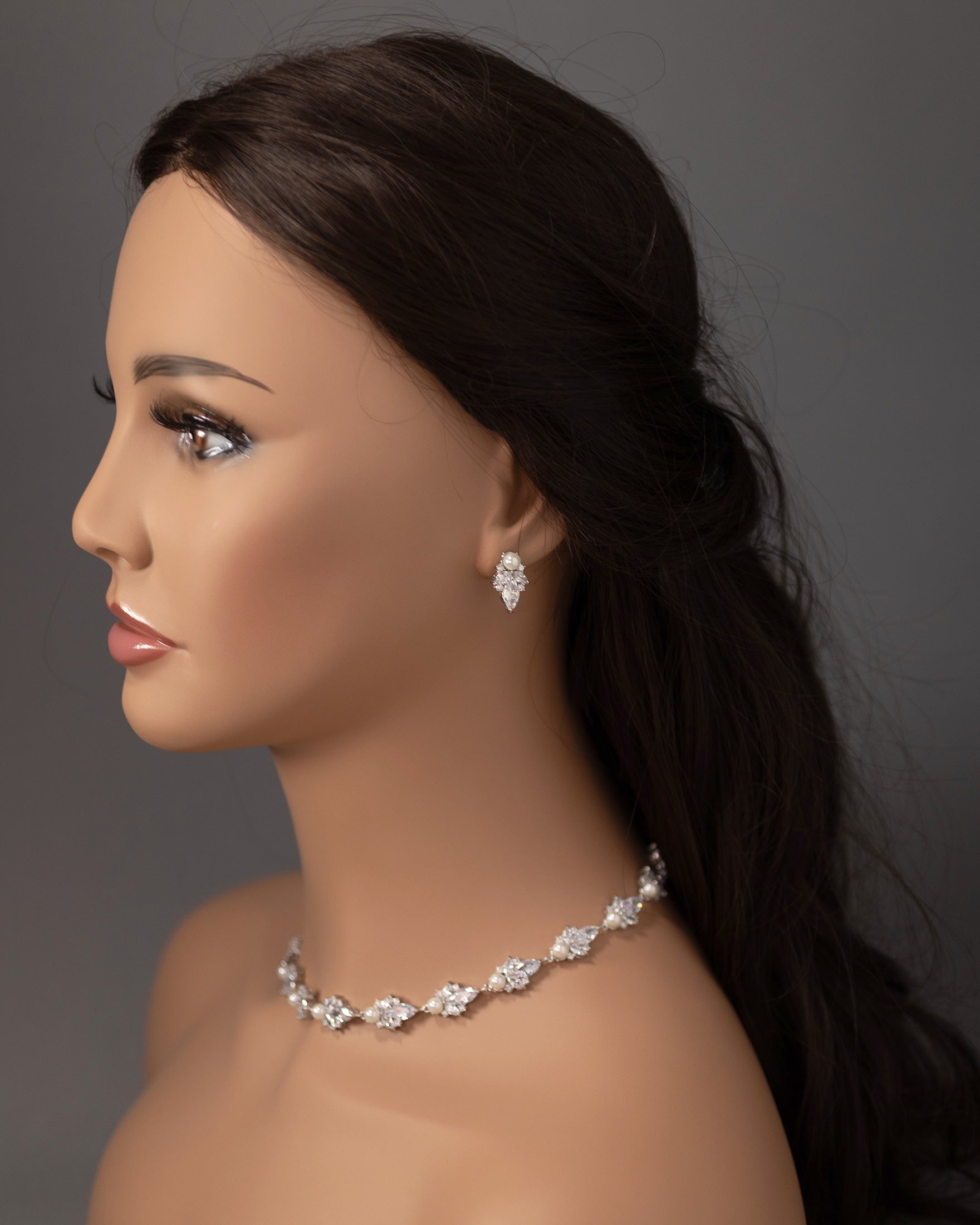 Mannequin head with jewelry including a necklace and earrings on a gray background