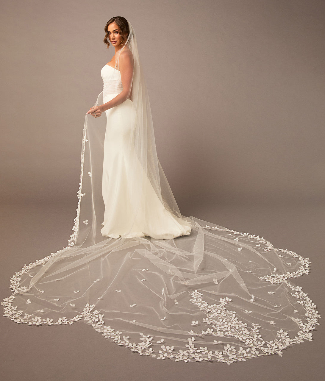 Clover Cut Regal Cathedral Veil with Organza Vines Bride wearing a long, elegant wedding veil with floral details on a plain background