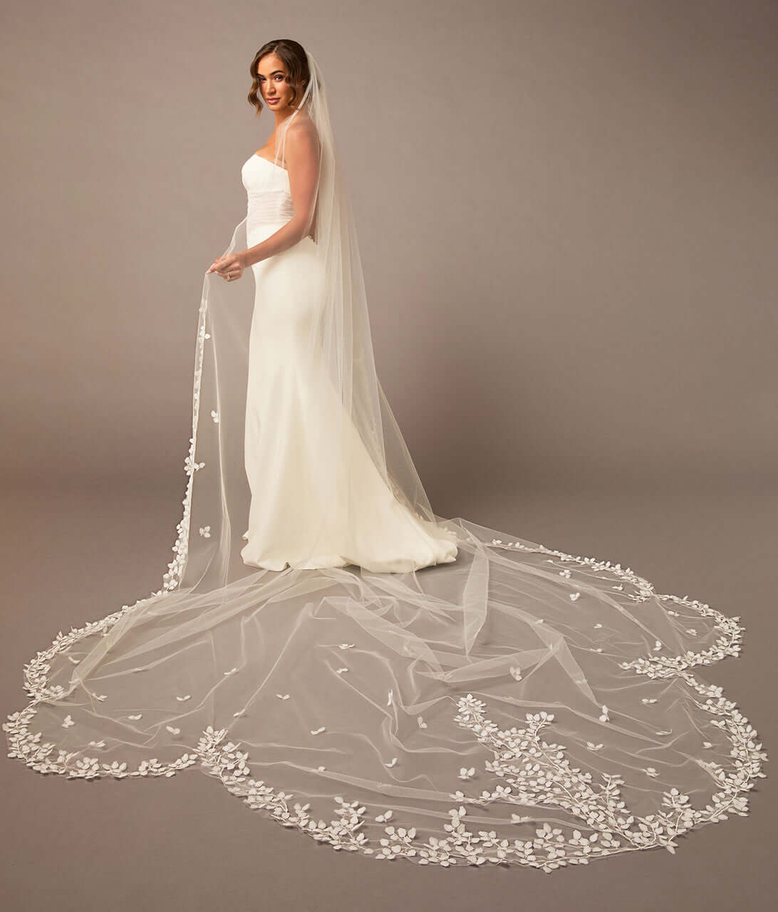 Clover Cut Regal Cathedral Veil with Organza Vines Bride wearing a long, elegant wedding veil with floral details on a plain background