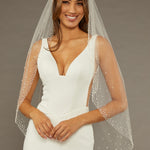 Fingertip Veil with Dense Scatter of Pearls Woman wearing a wedding dress with a veil against a brown background