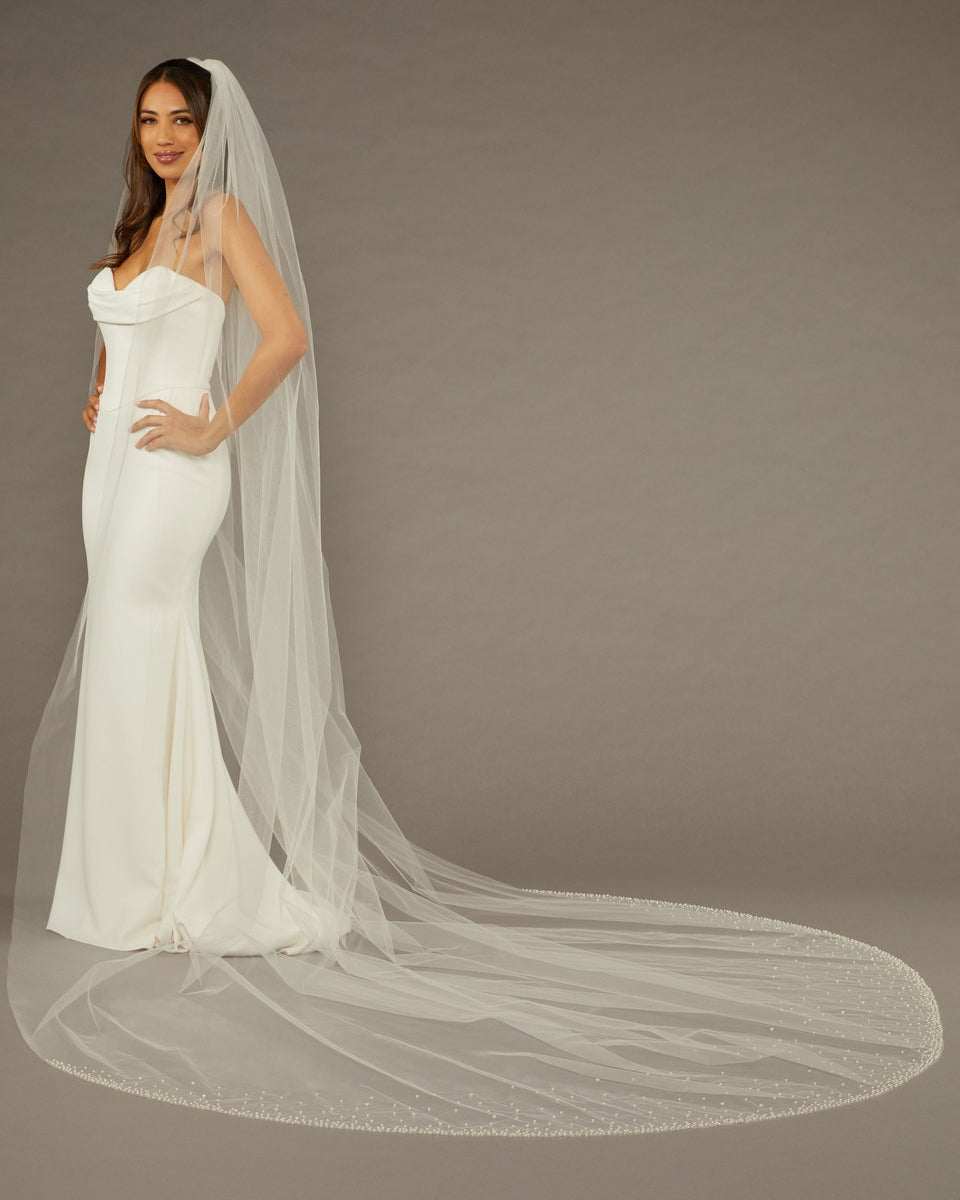 Wide Cathedral Veil with Dense Scatter of Pearls Woman wearing a wedding dress with a long veil on a brown background