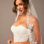 Waltz Wedding Veil with Alencon Lace Woman wearing a white wedding dress with a lace veil against a neutral background