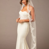 Waltz Wedding Veil with Alencon Lace Woman wearing a white wedding dress with a lace veil against a brown background