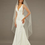 Waltz Waterfall Veil with Pearls and Sequins Woman wearing a wedding dress with a long veil against a brown background