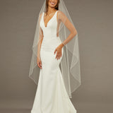 Waltz Waterfall Veil with Pearls and Sequins Woman wearing a wedding dress with a long veil against a brown background
