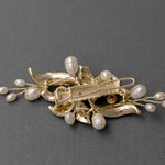 Gold brooch with pearls on a gray background