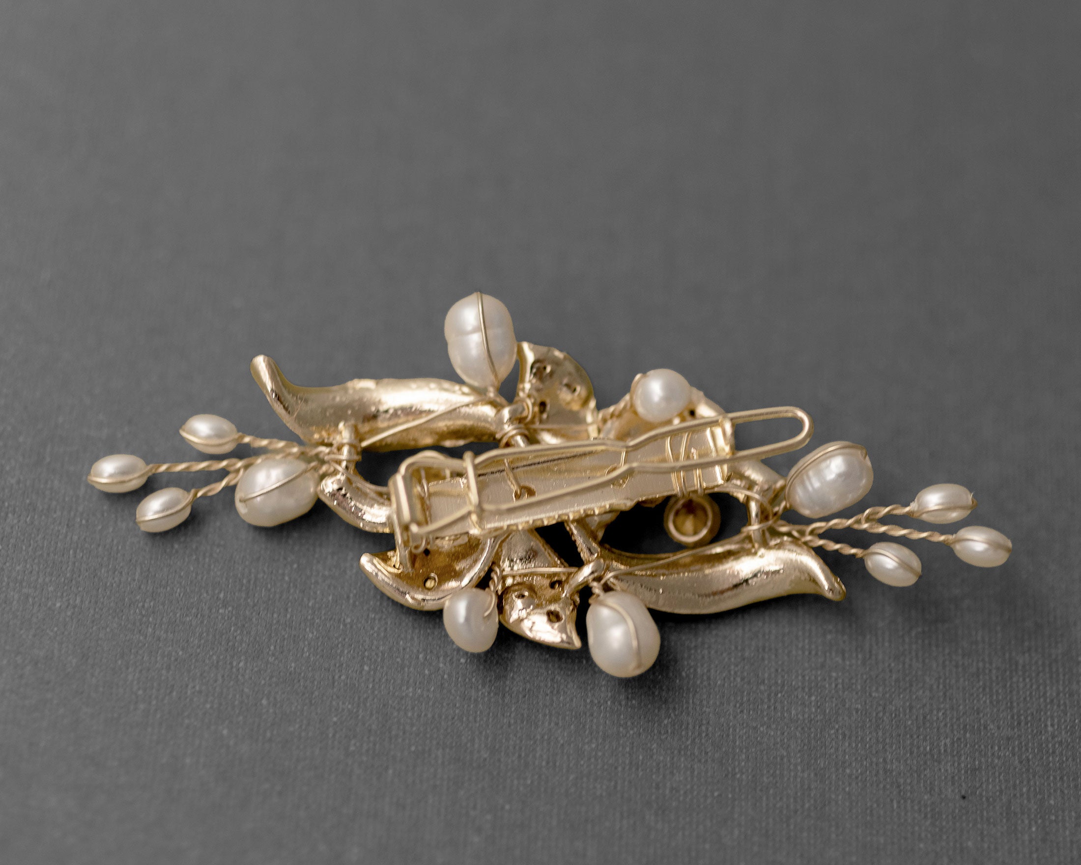 Gold brooch with pearls on a gray background