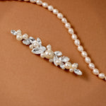 Bridal Bobby Pin with Marquise Jewels & Pearls A pearl floral hairpiece with clear rhinestones and faux pearls, displayed on a warm brown textured background.