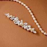 Bridal Bobby Pin with Marquise Jewels & Pearls A pearl floral hairpiece with clear rhinestones and faux pearls, displayed on a warm brown textured background.