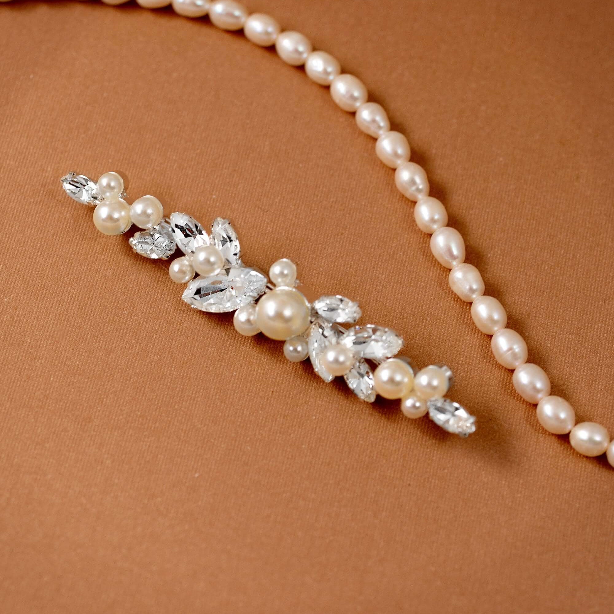 Bridal Bobby Pin with Marquise Jewels & Pearls A pearl floral hairpiece with clear rhinestones and faux pearls, displayed on a warm brown textured background.