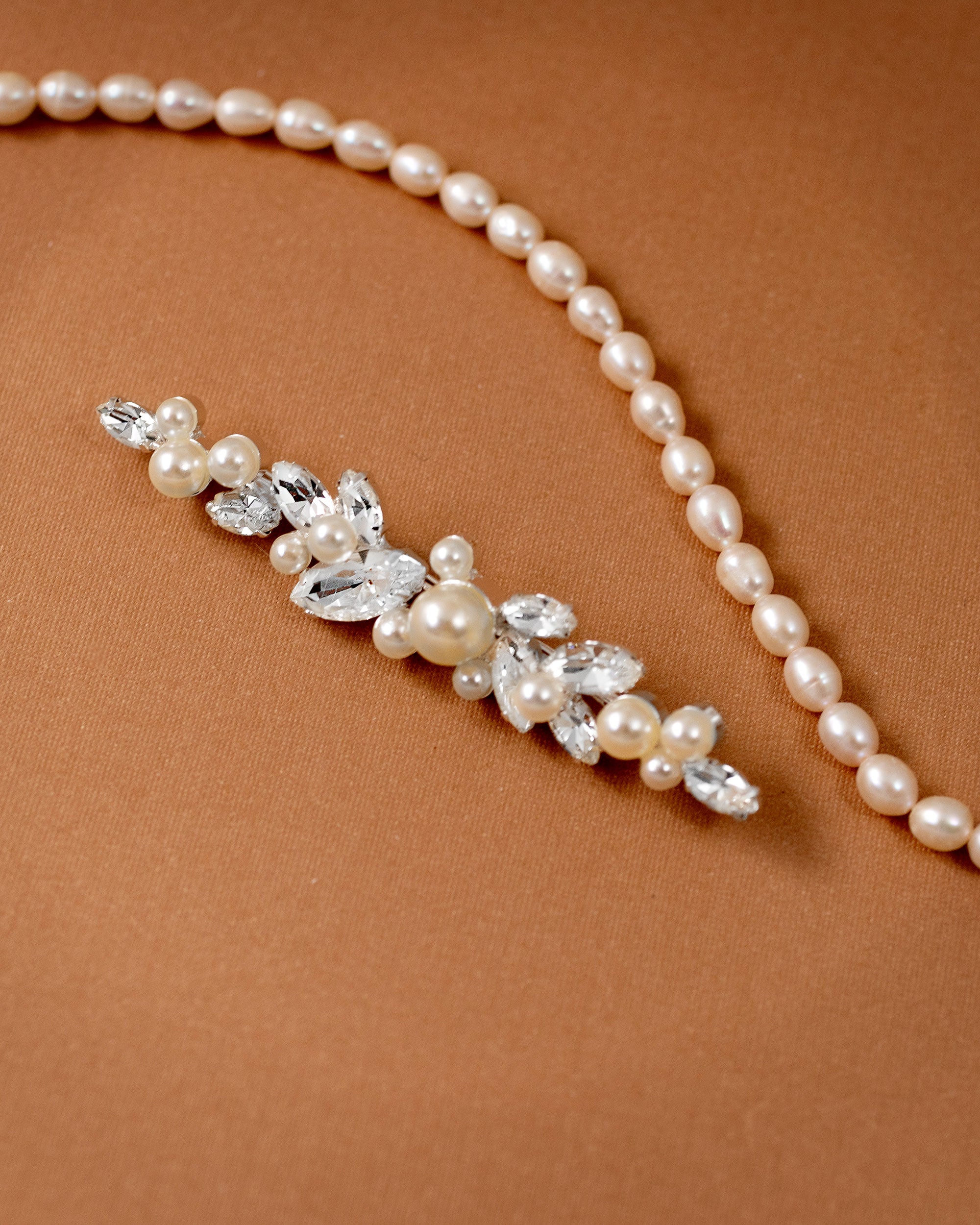 Bridal Bobby Pin with Marquise Jewels & Pearls A pearl floral hairpiece with clear rhinestones and faux pearls, displayed on a warm brown textured background.