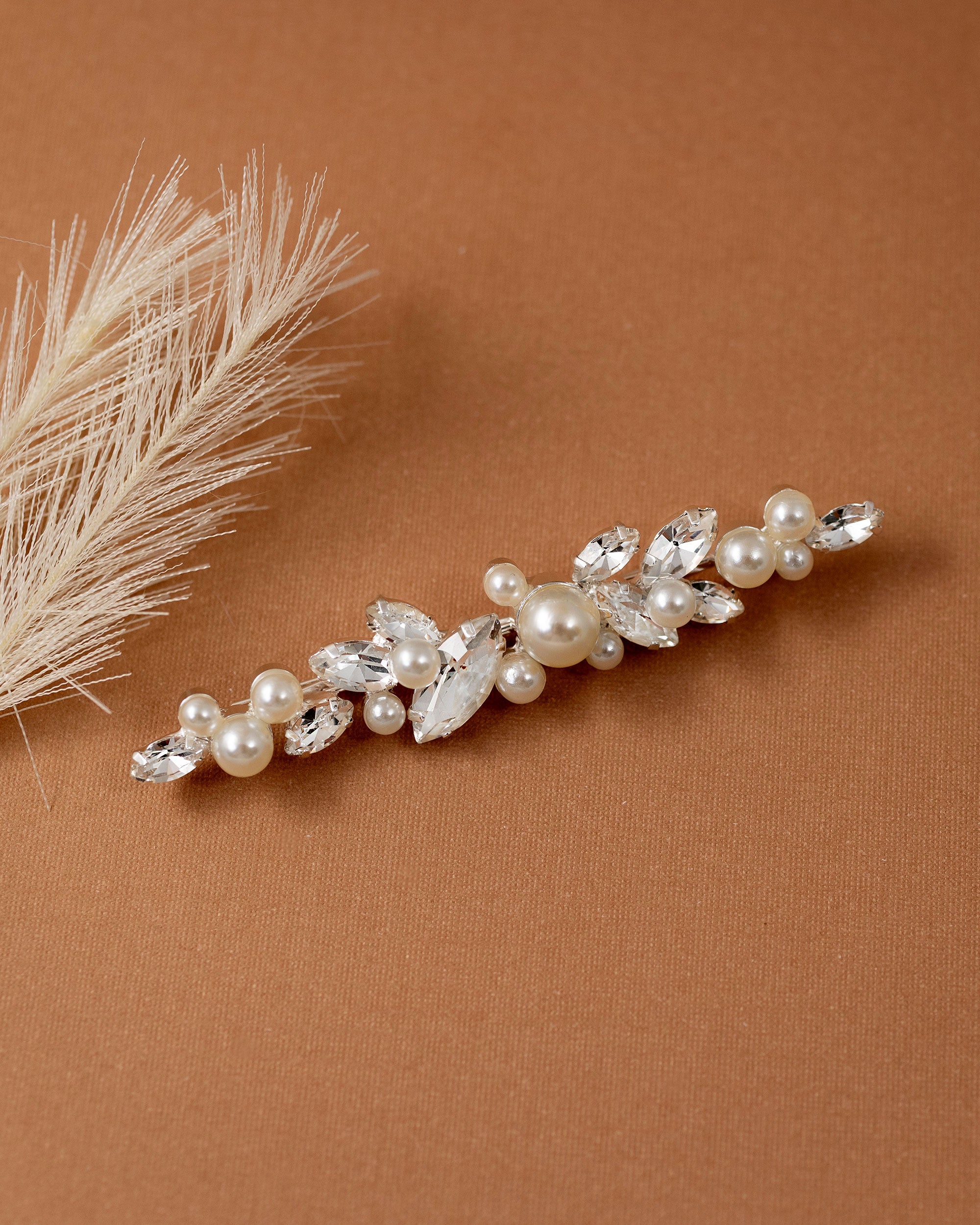 Bridal Bobby Pin with Marquise Jewels & Pearls A bridal hair claw clip decorated with faux pearls and clear marquise and round crystals, styled on a warm brown textured background with dried pampas grass.