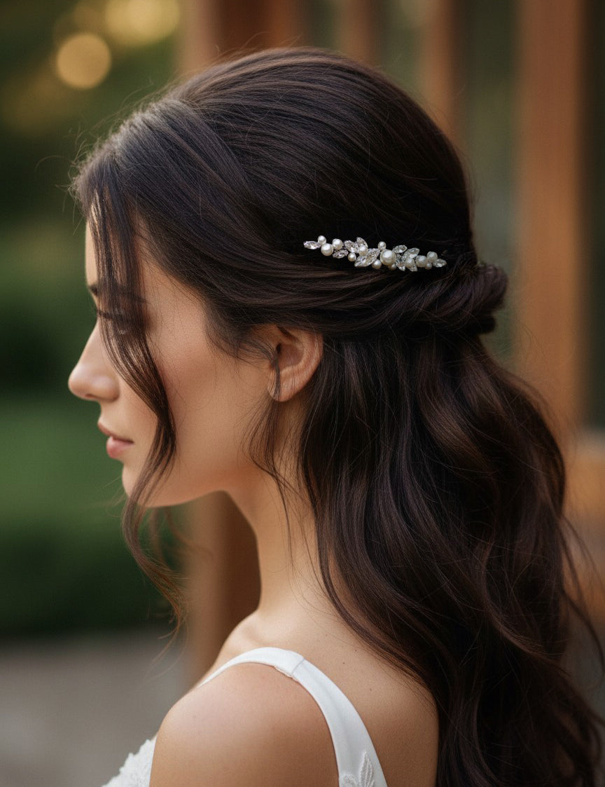 Bridal Bobby Pin with Marquise Jewels & Pearls A woman in profile with long dark brown hair wearing a delicate silver bridal hair accessory with clear stones, set against a softly blurred warm-toned background.