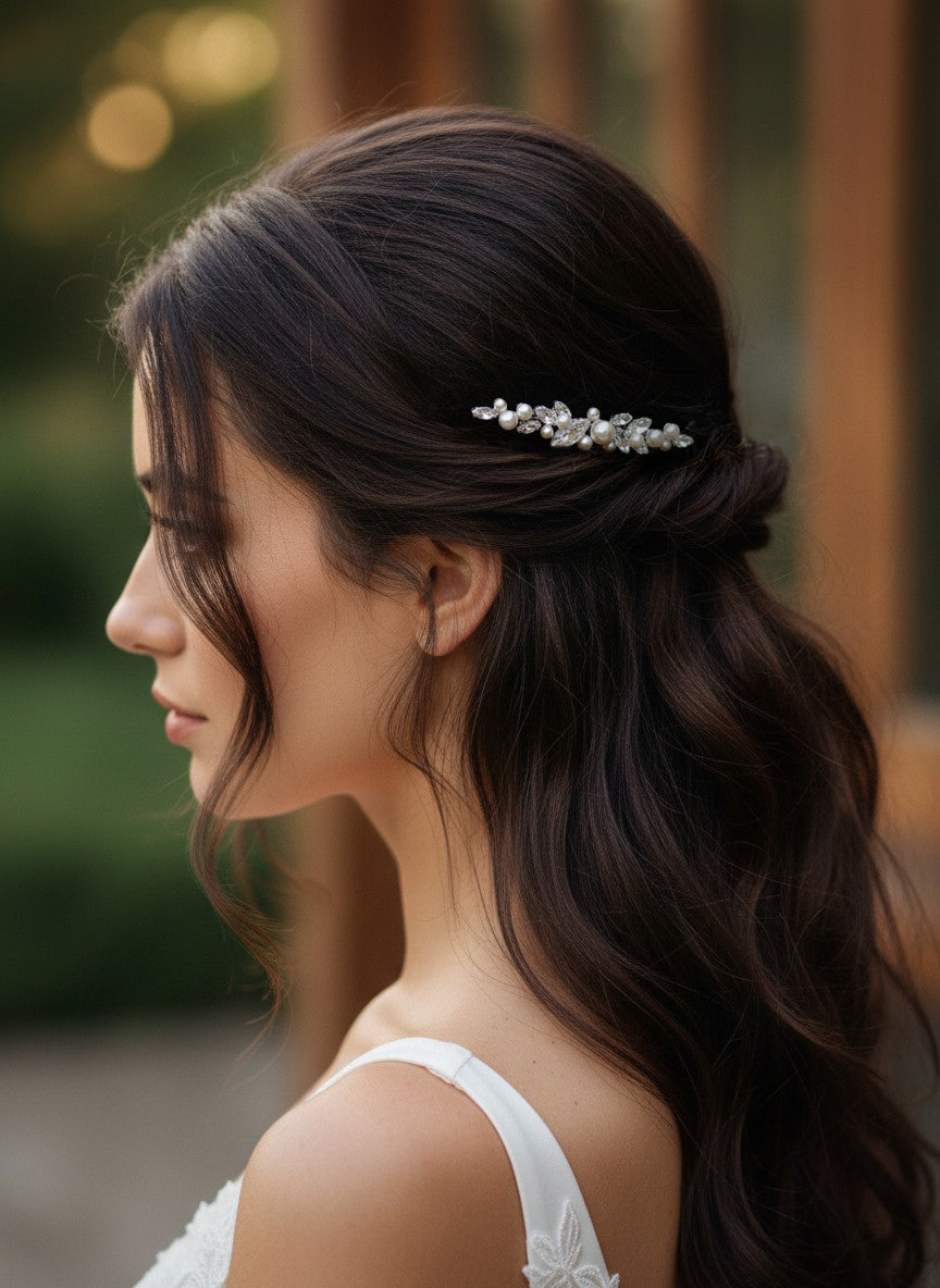 Bridal Bobby Pin with Marquise Jewels & Pearls A woman in profile with long dark brown hair wearing a delicate silver bridal hair accessory with clear stones, set against a softly blurred warm-toned background.